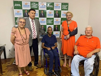 Grupo de pessoas da ATRADEF, incluindo pessoa com deficiência em cadeira de rodas, reunidas em confraternização.